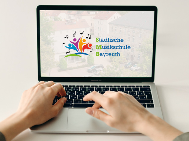 Laptop mit Händen und im Bildschirm das Musikschul-Logo –Digitaler Tag der offenen Tür – Musikschule Bayreuth